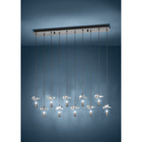 Comareira ten-light linear pendant in black nickel, with a long steel canopy, slim drops, cylindrical shades and clear faceted glass leaf details, shown against a dark blue studio background.