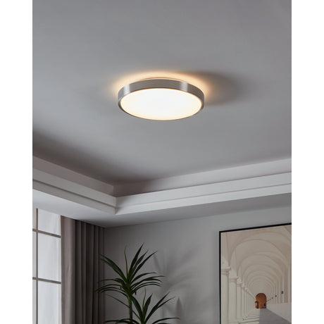 Competa 43cm round LED flush ceiling light with white diffuser and satin nickel band, shown illuminated on a grey ceiling in a hallway setting.