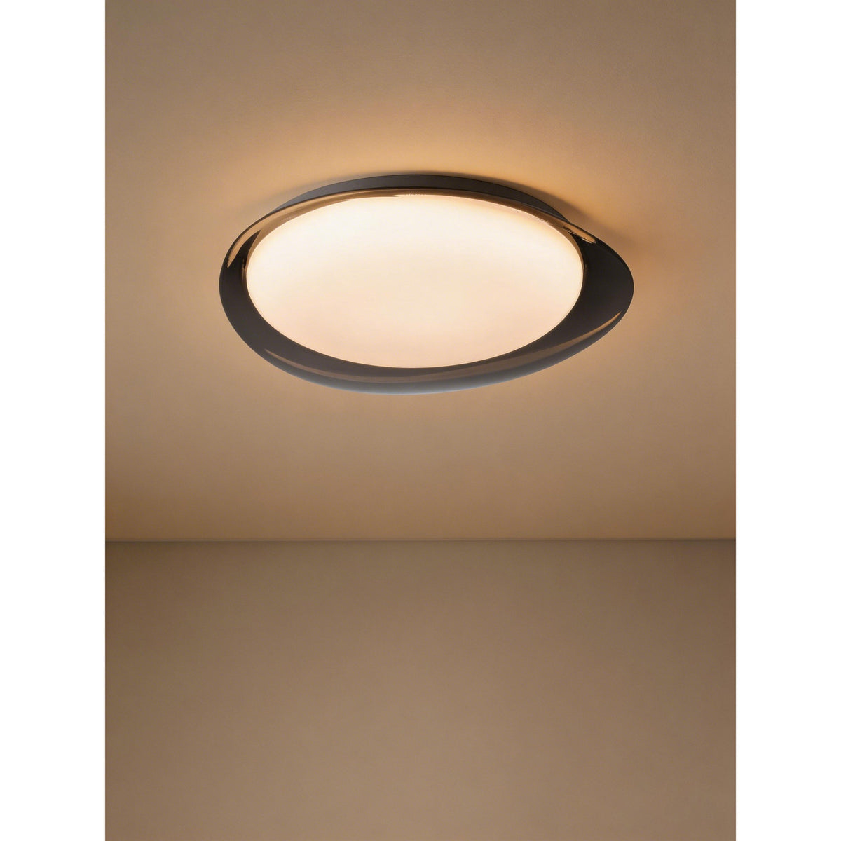 Conistarino 40cm LED flush ceiling light with an organic pebble-shaped grey frame and white diffuser, glowing warmly on a hallway ceiling.