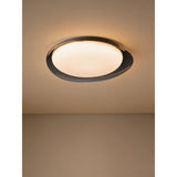 Conistarino 40cm LED flush ceiling light with an organic pebble-shaped grey frame and white diffuser, glowing warmly on a hallway ceiling.