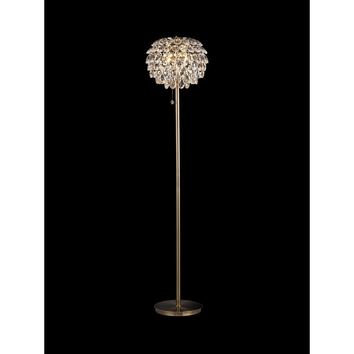 The Coniston 3 Light Crystal Floor Lamp in Antique Brass features a slim stand, round base, and a decorative shade with hanging crystal-like elements for a sparkling, elegant look against a black background.