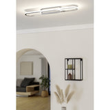 Conivarena LED flush ceiling light in chrome, an elongated oblong loop with a central chrome bar, mounted on a hallway ceiling with white walls and an arched doorway.