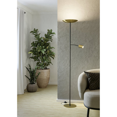 Conivarino mother and child floor lamp in black and brushed brass, with a tall uplighter dish and adjustable reading arm, shown beside a sofa in a living room.