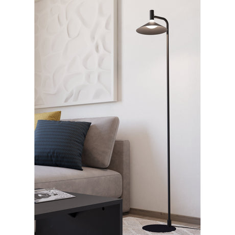 Conomavilla Smart LED Floor Lamp in black steel with slim curved stem, flat conical shade and round disc base, shown beside a sofa in a living room.