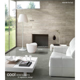 Modern living room featuring a white sofa, coffee table, and the Cool 2 Light Floor Lamp in matt white & opal white for ambient lighting. A unique chair sits by a minimalist fireplace. Large window reveals garden views; neutral tones enhance the calm vibe.
