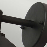 Close-up of a minimalist Copenhagen Outdoor Wall Lantern - Black. The round backplate and cylindrical arm, crafted in stainless steel, stand out against a light gray background. Its sleek design is complemented by an IP44 rating, ensuring durability for any modern space.