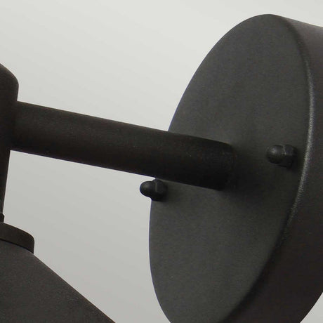 Close-up of a minimalist Copenhagen Outdoor Wall Lantern - Black. The round backplate and cylindrical arm, crafted in stainless steel, stand out against a light gray background. Its sleek design is complemented by an IP44 rating, ensuring durability for any modern space.