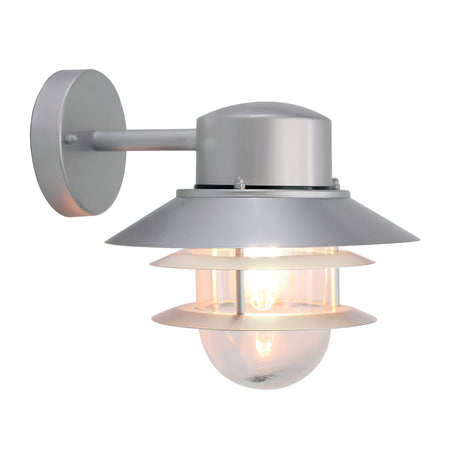 The Copenhagen Outdoor Wall Lantern - Silver features a sleek, Scandinavian design with a metallic finish and layered shade. Crafted from stainless steel, the light bulb is visible through a glass cover, elegantly mounted on a circular base for a contemporary appearance.
