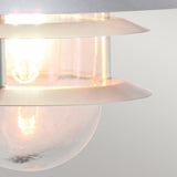 Here's a rewritten version of the sentence based on the given product data:

"Close-up of the Copenhagen Outdoor Wall Lantern - Silver, featuring a glowing bulb within a cylindrical glass shade accented by stainless steel rings. The Scandinavian design highlights a sleek, minimalist aesthetic with soft illumination.