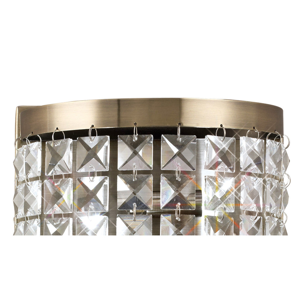 Close-up of Diyas Cortina 2 light crystal wall light in antique brass, showing the curved top band and grid of clear faceted crystal squares.
