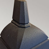 Close-up of the Chapel-1 1 Light Outdoor Wall Lantern in black, showcasing its dark, angular structure crafted from sleek die-cast aluminum. The design features geometric, stepped shapes reminiscent of a modern half-lantern sculpture set against a neutral background, highlighting the elegance of this outdoor wall light.