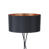 Crelvane Floor Lamp in black, close-up of the tripod steel legs crossing beneath a wide black fabric drum shade with a copper-lined interior, shown against a plain white background.