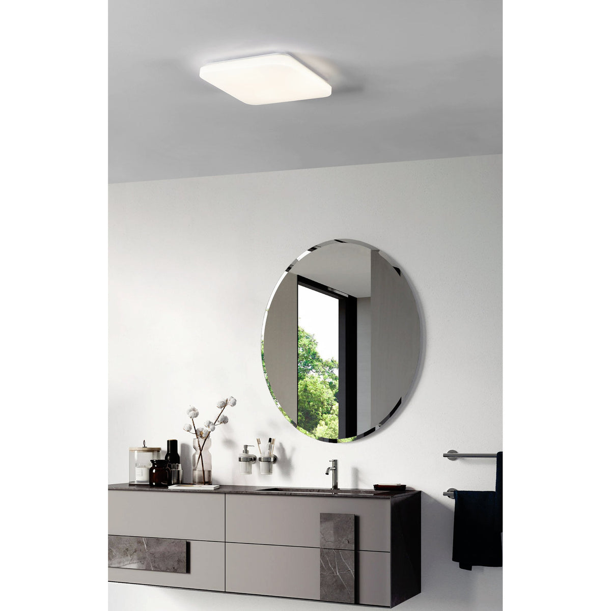 Crelvette LED Bathroom Ceiling Light, a square white flush fixture with rounded corners and opal diffuser, shown installed above a round mirror in a modern bathroom.
