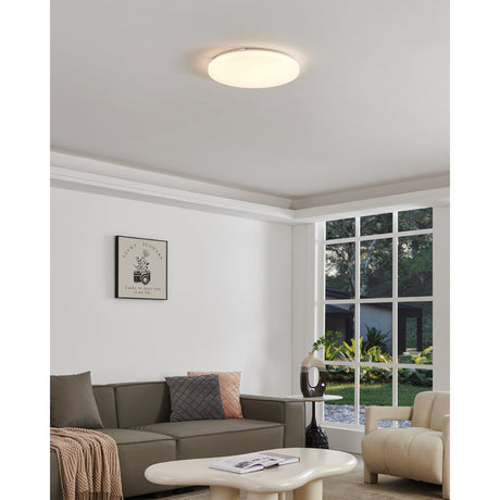 Crelvette LED Flush Ceiling Light 43cm in white, round opal diffuser mounted close to the ceiling, shown illuminated in a living room with sofa, armchair and large window.