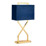 The Cross Table Lamp With Blue Shade - Polished Gold features a sleek, blue oblong shade atop a striking geometric design with a polished gold base, all elegantly showcased against a white background.