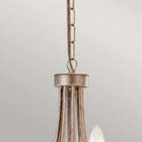 A close-up of the Christina 8 Light Chandelier showcases its elegant design with a Silver and Gold patina finish. The chandelier is suspended by a chain, featuring candle-like bulbs complemented by subtle crystal details, all set against a plain gray background.