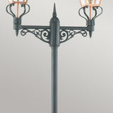 The Chelsea Twin Head Lamp Post - Copper & Black showcases a black, ornate design with two lanterns and decorative scrollwork beneath each light. Its angular lighting shines through clear panels, highlighting intricate details in dazzling Copper & Black tones against a neutral backdrop.