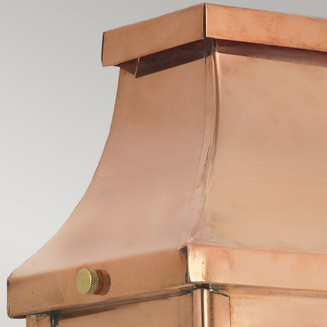 A close-up view of the Chelsea Outdoor 1 Light Large Half Lantern - Copper reveals its elegantly smooth, curved design that resembles a copper chimney cap. The polished metallic surface reflects light brilliantly, and a small round adjustment knob on one side stands out against the neutral gray background, enhancing the lantern's elegance.