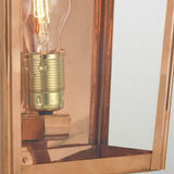 The Chelsea Outdoor 1 Light Large Half Lantern - Copper, featuring a vintage-style light bulb with a brass base, elegantly showcases the bulb's intricate details while its weather-resistant design beautifully reflects light.