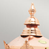 A close-up of the top portion of the Chelsea Outdoor 1 Light Half Lantern - Copper showcases its polished finish with decorative details and a pointed design. The smooth, shiny copper surface reflects the light beautifully, set against a plain background.