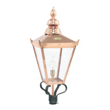 The Chelsea 1 Light Grande Lamp Post Head - Copper is a beautifully crafted outdoor lighting piece featuring a vintage copper lantern design with a pointed top and clear glass panels that reveal the light bulb inside. This elegant lamp post head is mounted on a black base, highlighting its classic design.