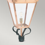 The Chelsea 1 Light Grande Lamp Post Head - Copper is an elegant outdoor lighting option featuring a vintage-style design with a copper lamp head. It includes four clear glass panels that encase a single bulb, along with a decorative dark metal mounting base set against a light gray background.