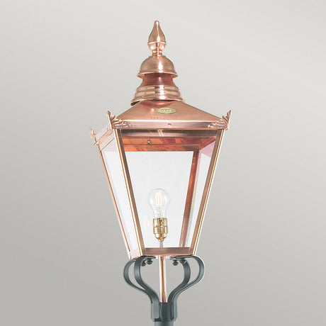 The Chelsea 1 Light Grande Lamp Post in copper and black offers an elegant outdoor lantern design with a classic aesthetic, featuring clear glass panels and a visible bulb, seamlessly integrated into an Outdoor Lighting setup on a sleek black post.
