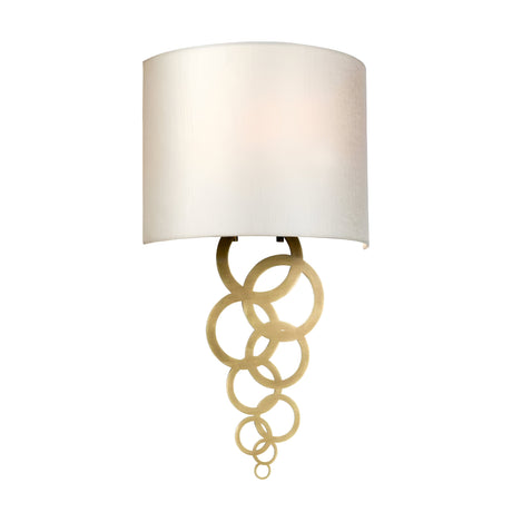 The Curtis Medium Wall Light - Aged Brass is designed with a sleek white cylindrical shade and stylish aged brass interlocking rings. Its contemporary design effortlessly complements different interior styles, bringing a touch of sophistication to any room.