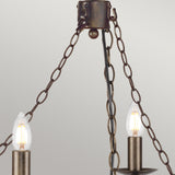 Close-up of the Cromwell 6 Light Chandelier in Old Bronze, showcasing its vintage-style design with two candle-shaped light bulbs suspended by three bronze chains. It stands elegantly against a plain light gray background.