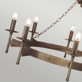 Close-up of a Cromwell 8 Light Chandelier in an Old Bronze finish, showcasing candle-like bulbs and a medieval lighting design. Eight lights are elegantly arranged on a circular metal frame, suspended by a chain against a plain light-colored background.