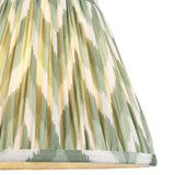 Endon Daneton 25cm tapered lamp shade in pleated faux silk with a green and white zigzag print and taped edge detailing, shown illuminated.
