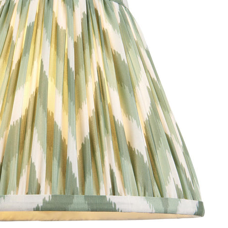 Endon Daneton 25cm tapered lamp shade in pleated faux silk with a green and white zigzag print and taped edge detailing, shown illuminated.