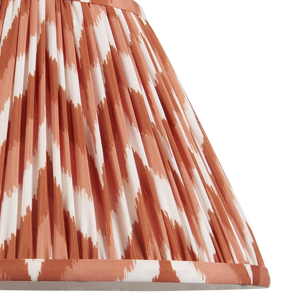 Close-up of Endon Daneton 30cm tapered lamp shade in pleated faux silk with an apricot orange and white zigzag print and taped edge detailing.