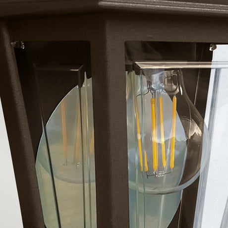 Here is a revised version of the sentence incorporating the provided product data:

The Deco Outdoor Wall Lantern - Bronze features a vintage-style clear glass light bulb with a visible filament, enclosed in a black metal and glass fixture. The bulb's illumination accentuates the lantern's elegant frame, evoking the classic sophistication of traditional outdoor wall lighting design.