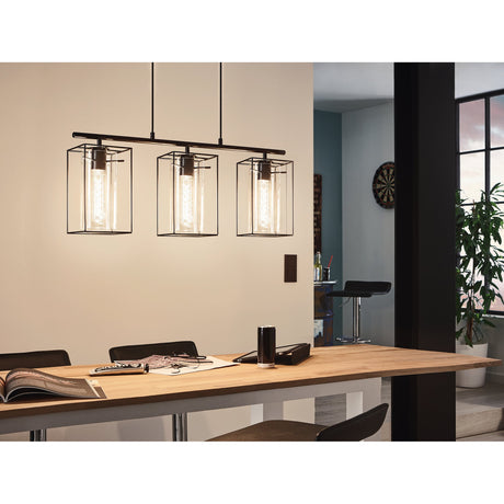 Dernane 3-light linear pendant light in black, with wire cage shades and smoked glass cylinders, suspended over a wooden dining table.