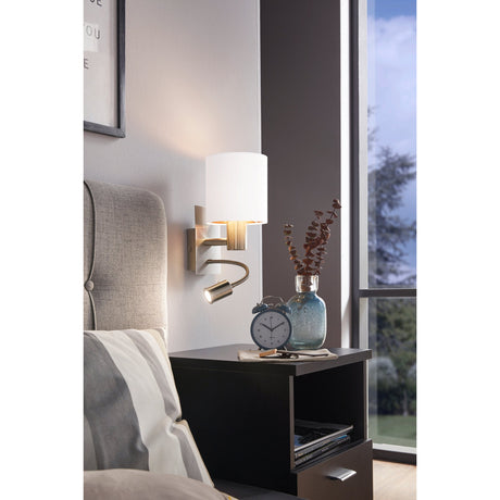 Dernessa LED Wall Light 15cm in satin nickel with white fabric drum shade and copper-lined rim, flexible reading arm below, shown beside a bed in a bedroom setting.