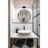 Dervette LED Bathroom Wall Light in black, a slim 40cm bar with white diffuser above a round mirror in a white-tiled bathroom with vessel sink and glass shower screen.