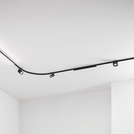 Deva 2m Surface 24V Lighting Track in black, shown curving across a white ceiling fitted with spotlights and a linear light module.