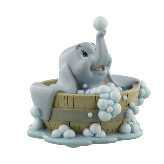 Hand painted resin figurine of Dumbo sitting in a wooden-look bubble bath tub, holding a bubble on his raised trunk, grey elephant with soapy bubbles, on a plain white background.