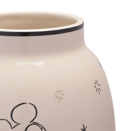 Close-up of a white ceramic vase's rim and shoulder, showing a black-banded open neck, glossy finish, scattered star details, and a sketched Mickey Mouse motif in black line art.