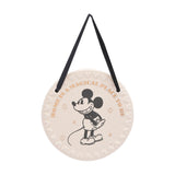 Round white ceramic wall plaque with a black Mickey Mouse illustration, gold "Home is a magical place to be" text, embossed Mickey head border, and black ribbon hanger on a plain background.