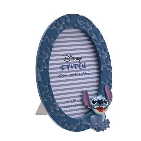 Oval freestanding resin photo frame in matt blue with a textured patchwork border and a 3D Stitch figure perched at the lower edge, holding a 6 x 4in striped insert card, shown on a white background.