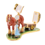 Belle & Phillipe Cottage Scene Metal Trinket Box, depicting Belle in a blue dress beside Phillipe the horse and an open hinged cart with wheels, on a green grass base against a plain white background.