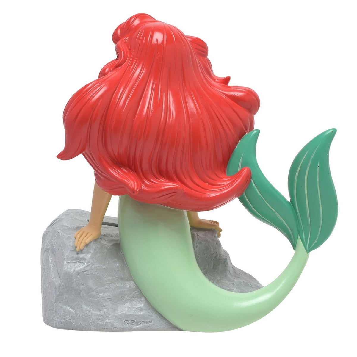 Rear view of the Ariel Mermaid Leaning on Rock resin money box, showing her flowing red hair, green curved tail with fin, and arms resting on a textured grey rock, on a plain white background.