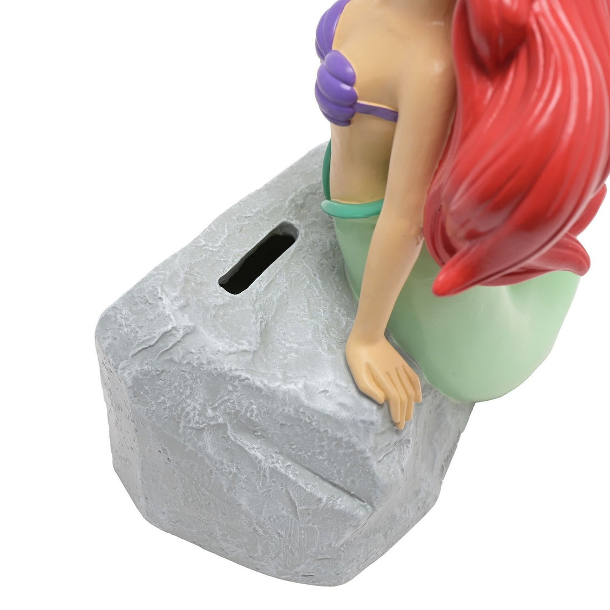 Close-up of the Ariel Mermaid resin money box showing her arm resting on the textured grey rock with the coin slot, green tail and red hair visible.