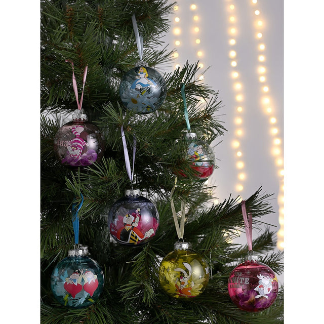 Seven round glass Christmas baubles in different colours on a tree, each featuring an Alice in Wonderland character including Alice, Mad Hatter, Cheshire Cat, and Queen of Hearts.