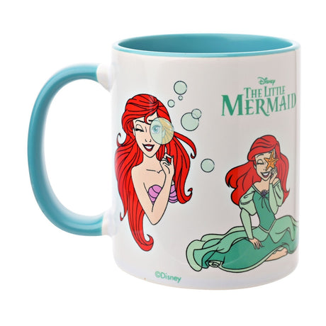 White stoneware mug with teal handle and interior, featuring Ariel from The Little Mermaid in red hair peeking through bubbles and seated in a green gown, on a white background.