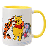 White stoneware mug with yellow interior and handle, featuring a printed scene of Winnie the Pooh, Tigger, Piglet and Eeyore embracing, on a plain background.