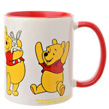 White stoneware Winnie the Pooh mug, 325ml, with red handle and interior, showing Pooh holding a toy rabbit and raising his arms, on a plain white background.