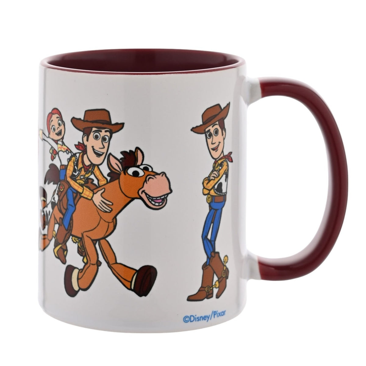 White stoneware mug with burgundy handle and interior, printed with Woody riding Bullseye alongside Jessie and a standing Woody in cowboy outfit, shown on a plain white background.